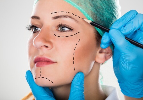 surgeon-drawing-perforation-lines-on-womans-face-picture-id842219874 surgeon-drawing-perforation-lines-on-womans-face-picture-id842219874